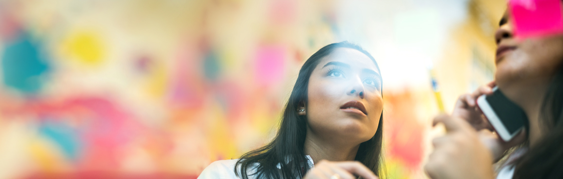 Woman looking at a glass wall with sticky notes on it