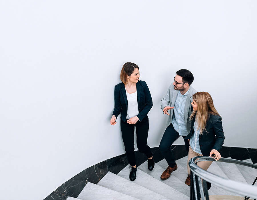 Three work colleagues walking up the stairs and talking